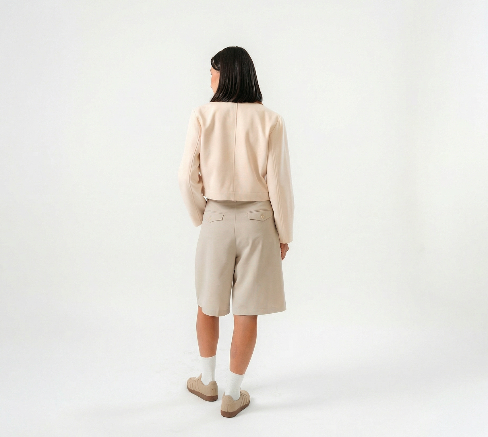 women wearing a beige biker jacket with full zip and bermuda pants with modern silhouette, design for daily city wear