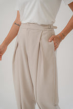 beige cross pleated pants with pocket and metal buckle details