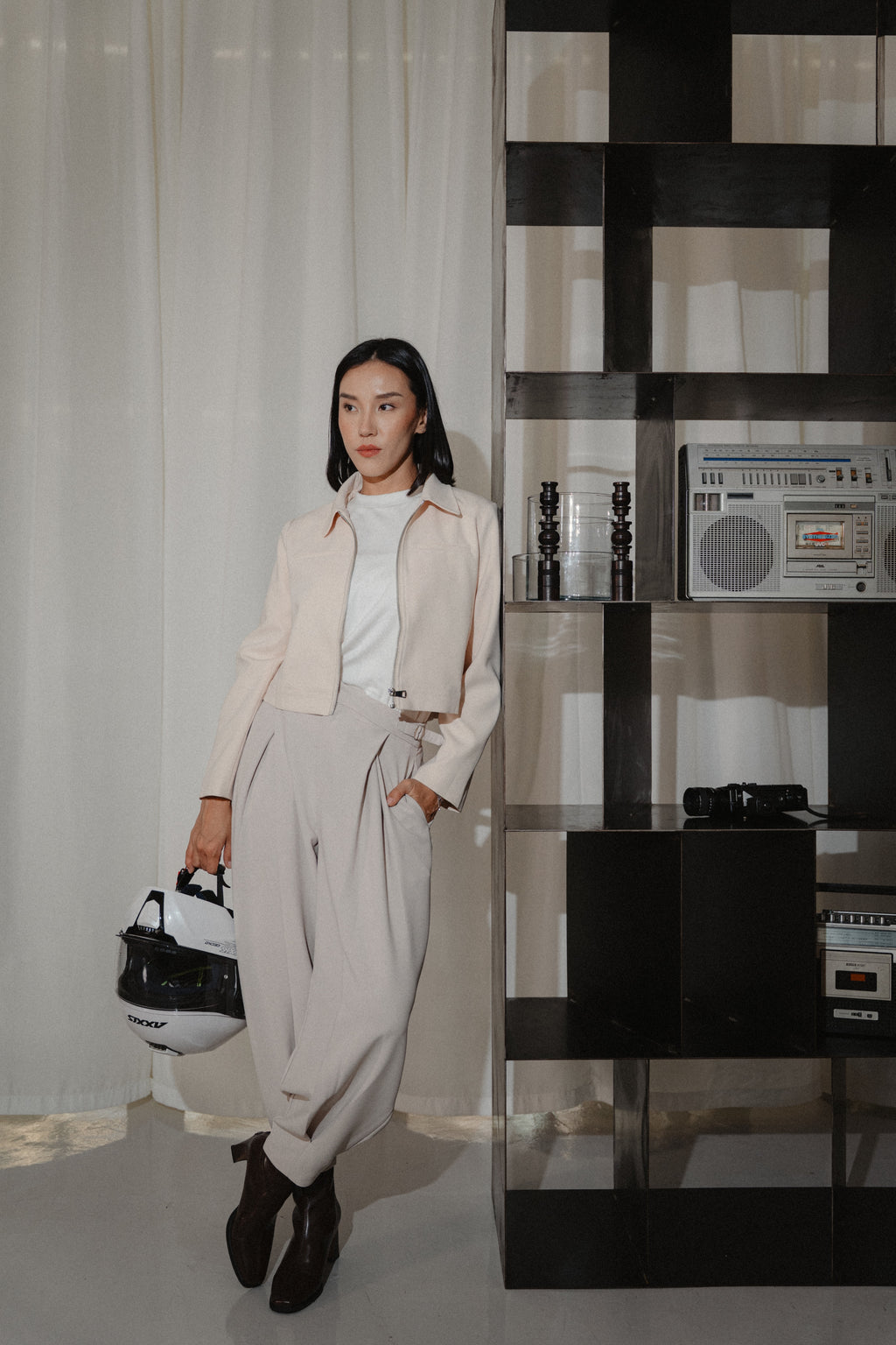 women wearing beige cross pleated pants, white crew neck tee and biker jacket with modern sillhoutte, design for daily city wear