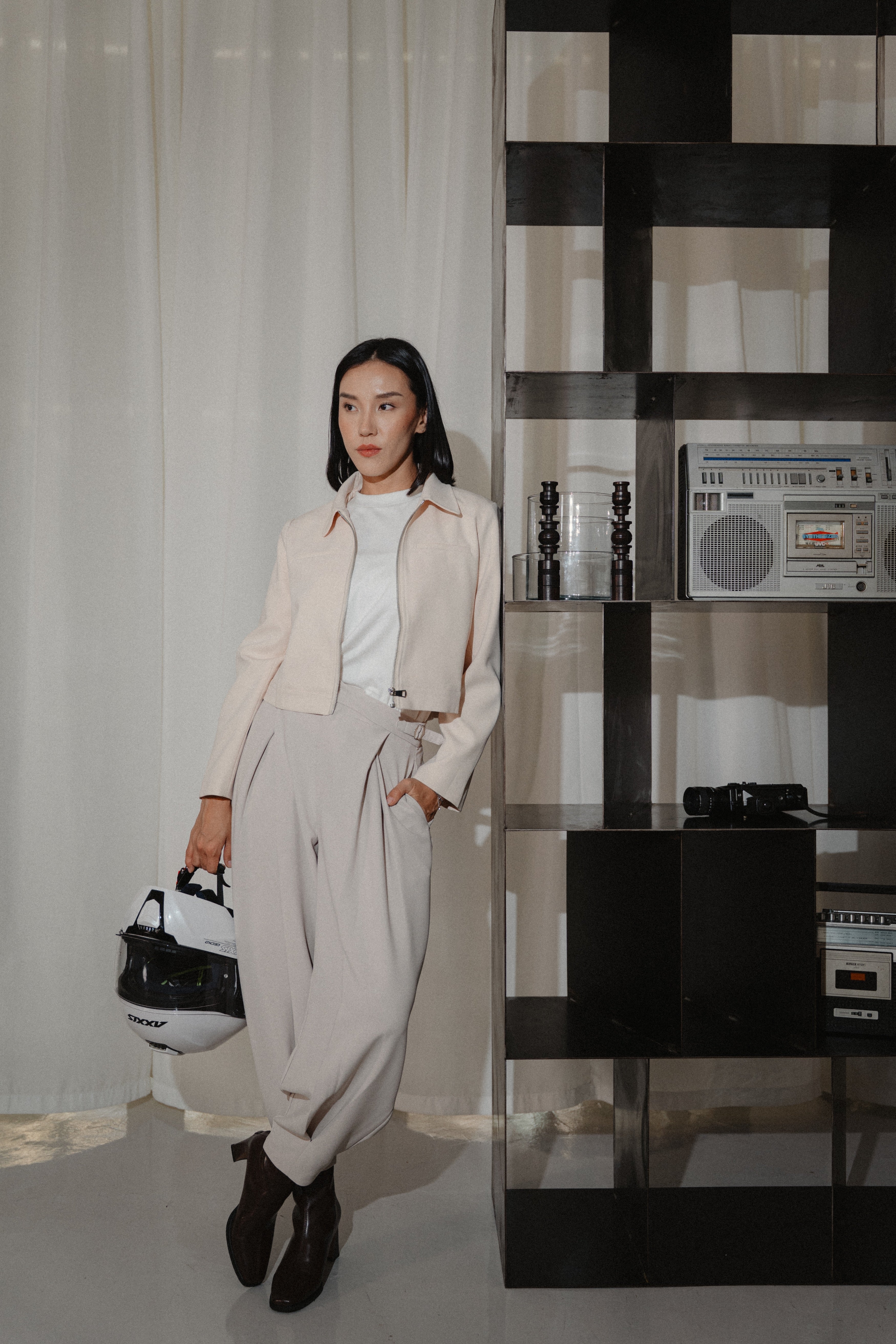 women wearing beige cross pleated pants, white crew neck tee and biker jacket with modern sillhoutte, design for daily city wear