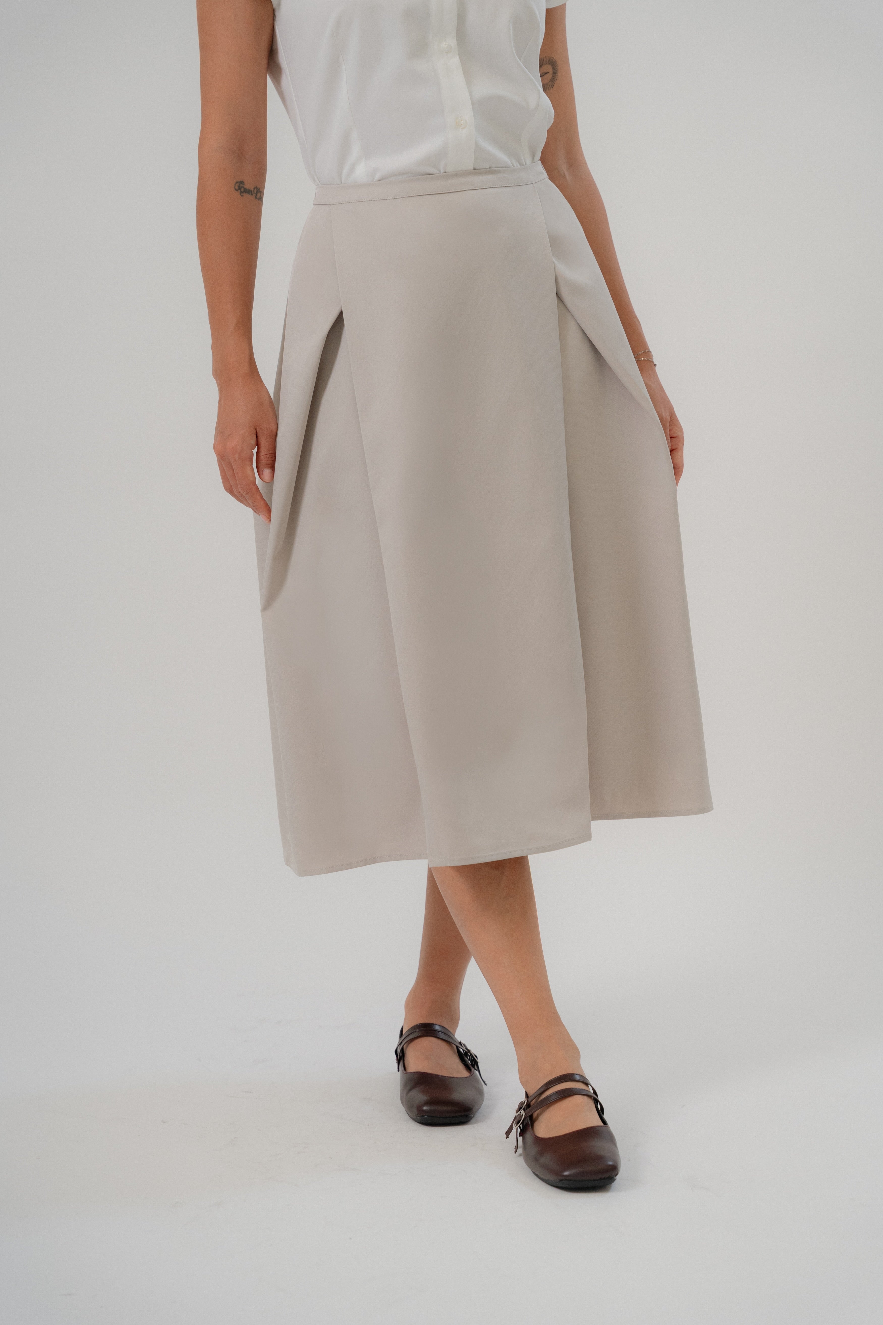 women wearing beige crossing pleated A-line skirt with clean fit, design without side cutline, suitable for daily and office wear