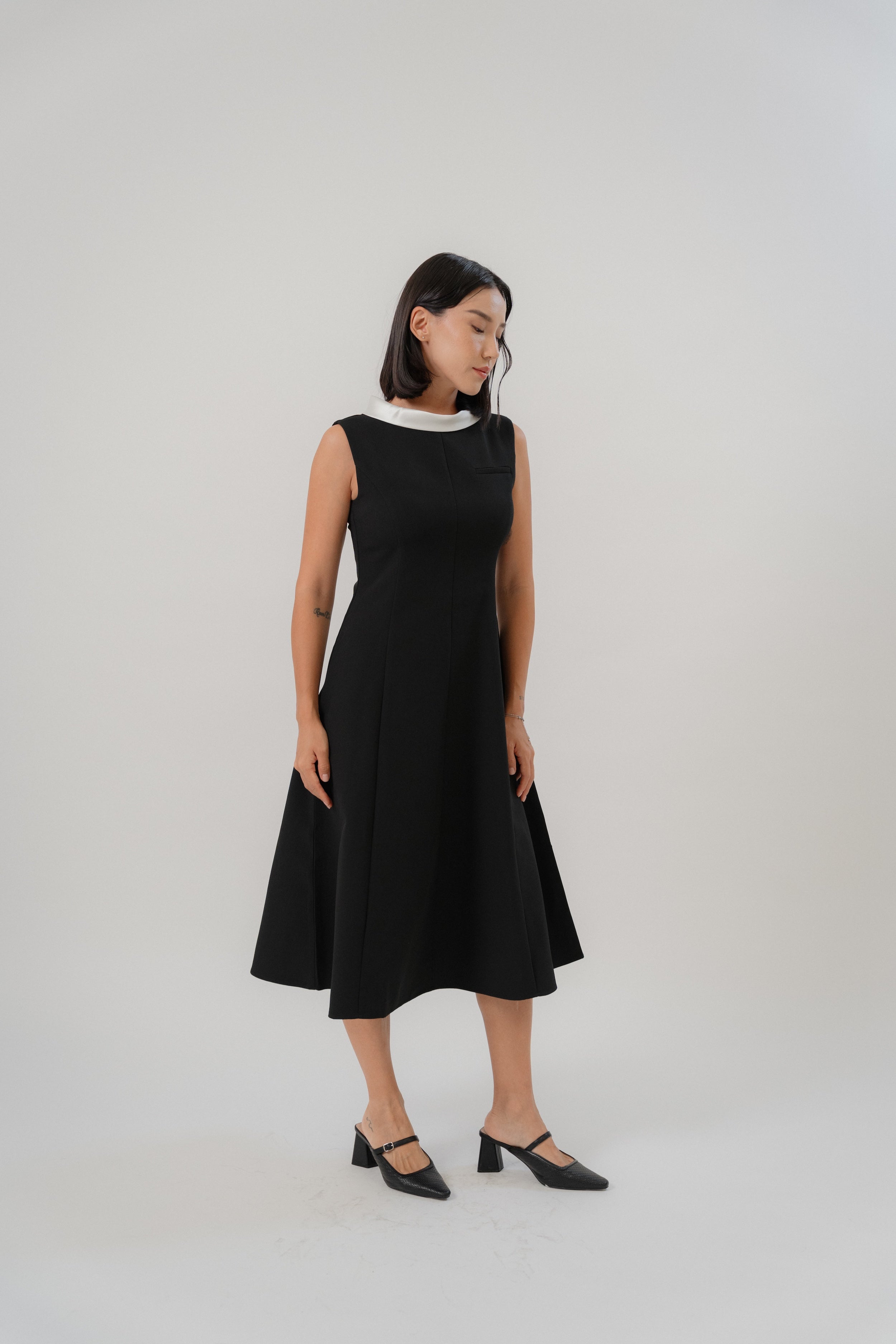 Woman wearing a black sleeveless maxi dress with white boat neck collar design, perfect for office wear