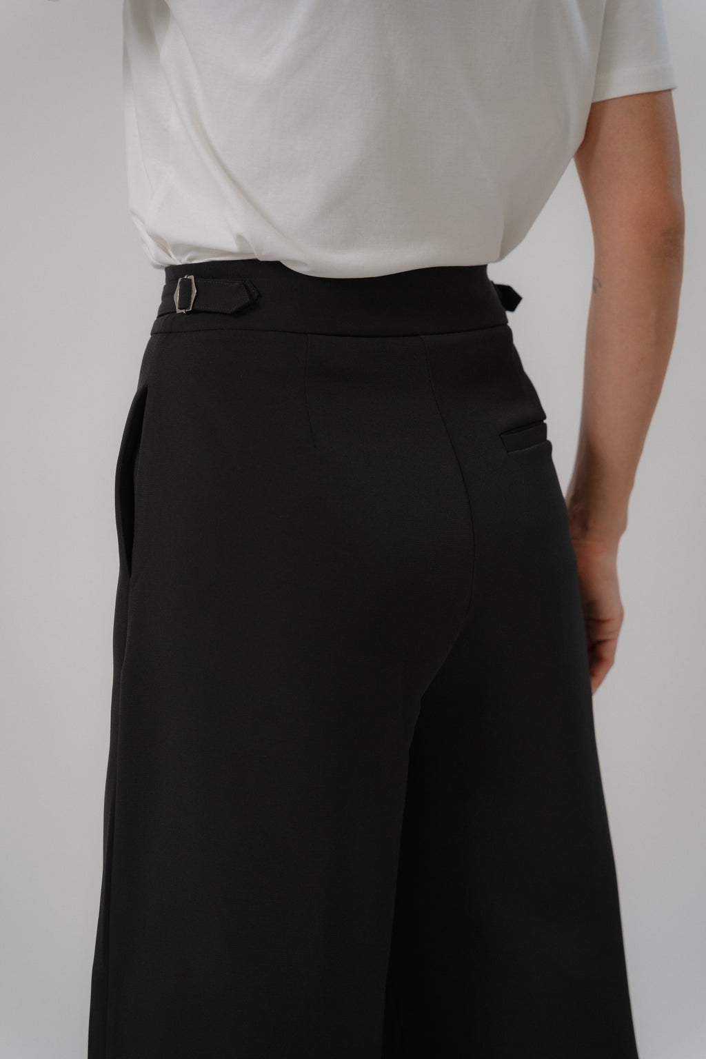 Black wide leg pants with wide leg cut, single front pleat, metal buckle straps, design for office and daily wear.