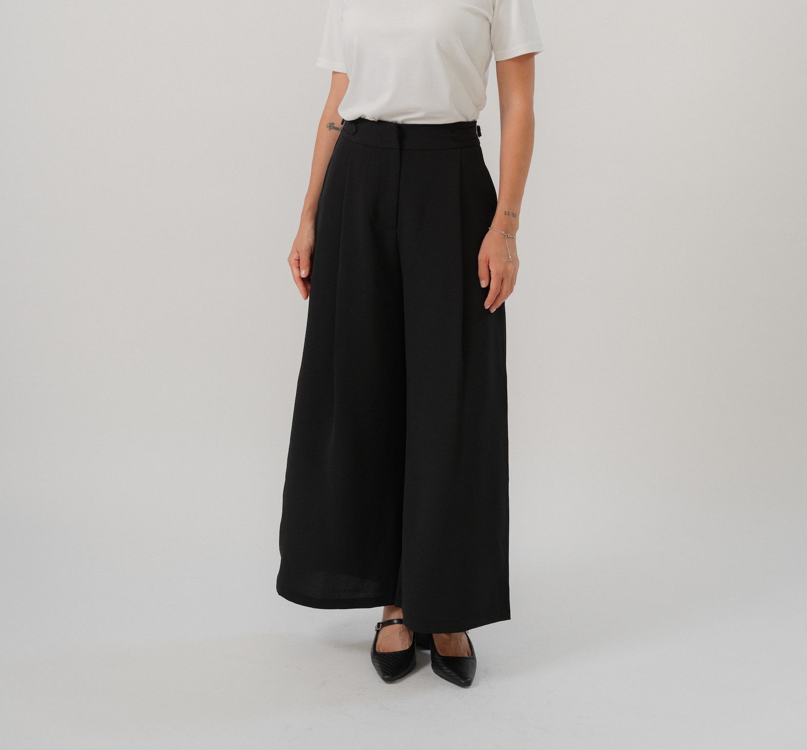 Black wide leg pants with wide leg cut, single front pleat, metal buckle straps, design for office and daily wear.