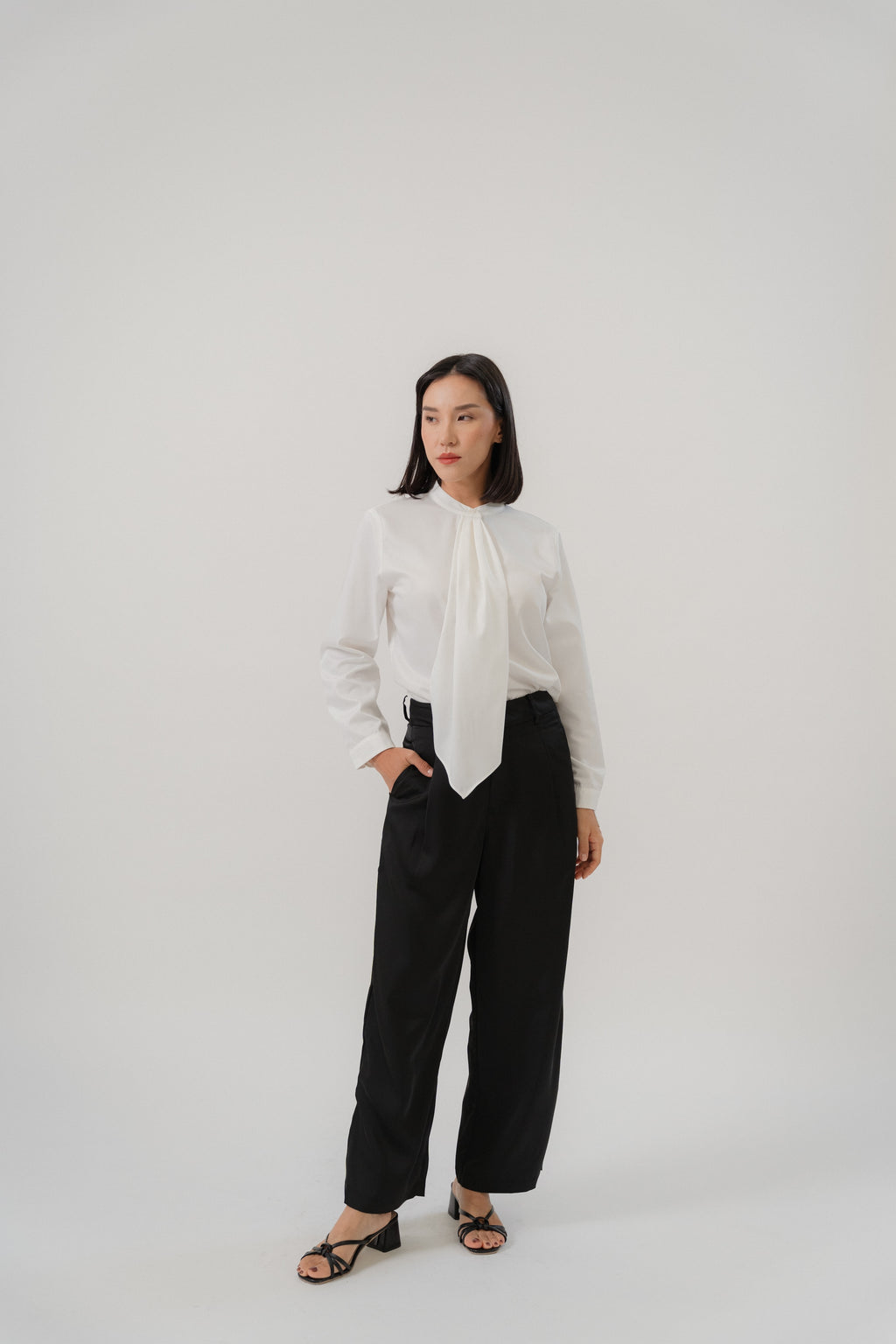 women wearing black satin pants and round neck collar tie blouse with classic blouse silhouette, design for office and city wear.